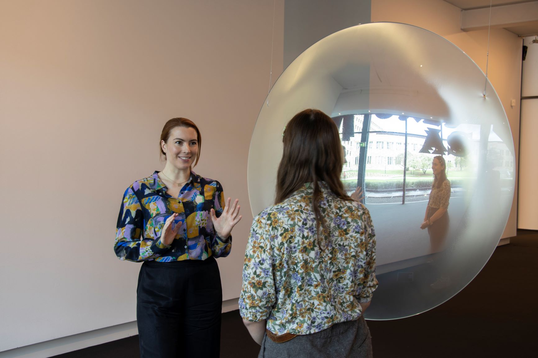 A mediator talking to a visitor in front of an artwork