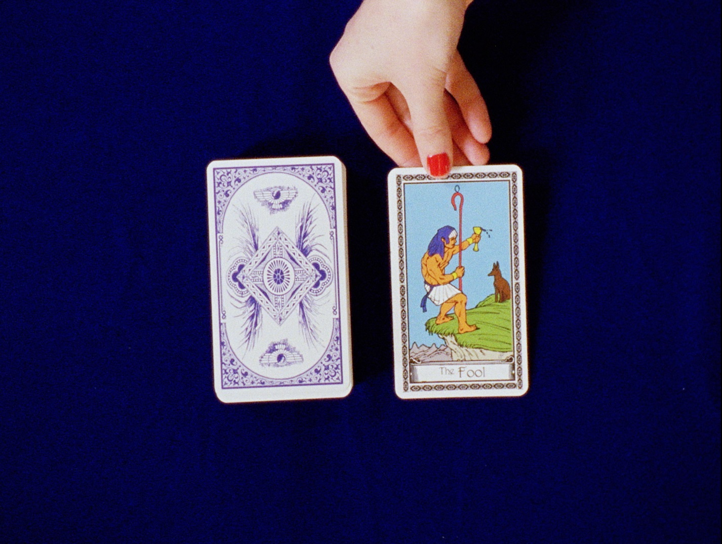 Film still showing two stacks of cards and a hand flipping one card over to face upwards