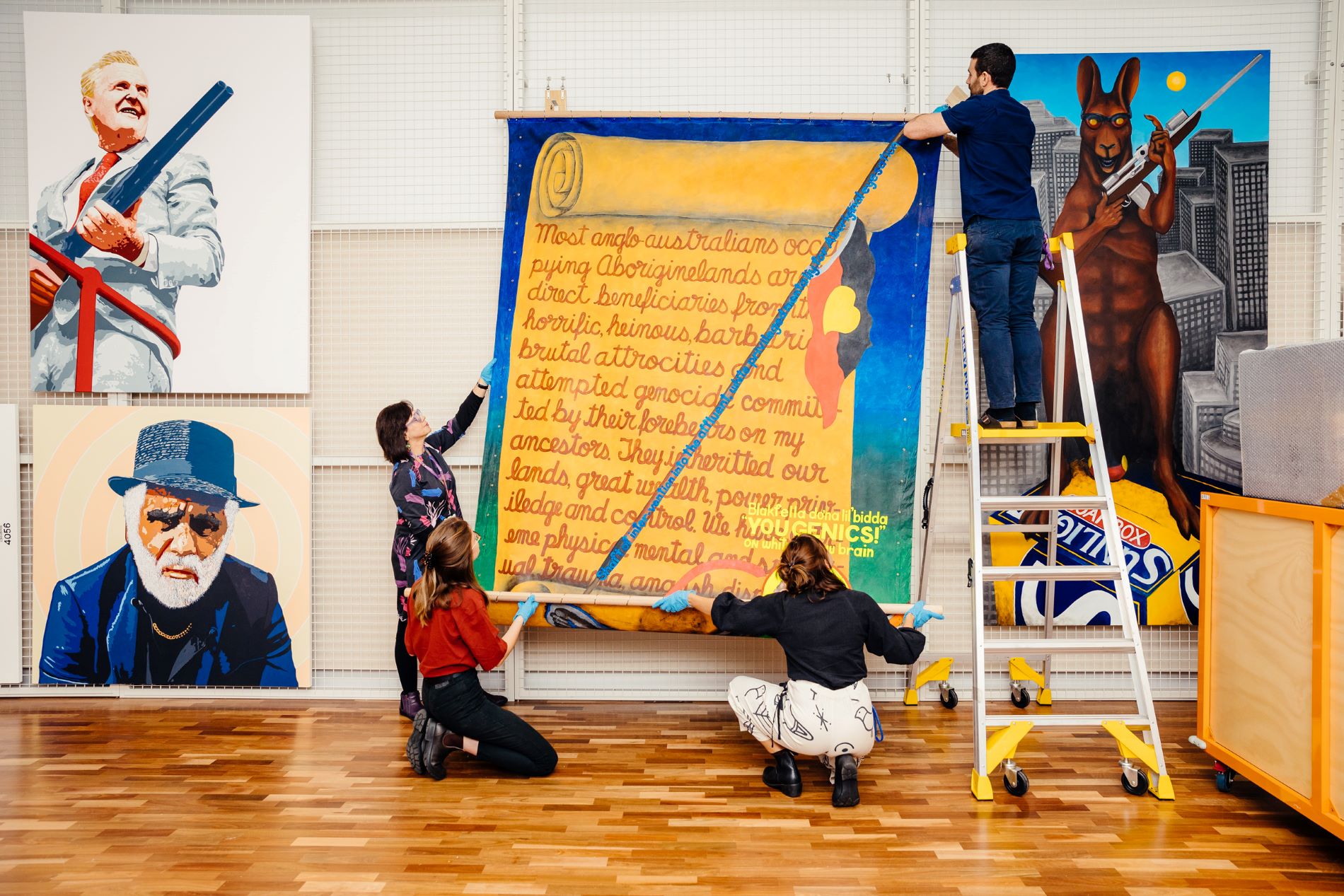 four people from the registration team hanging a large artwork