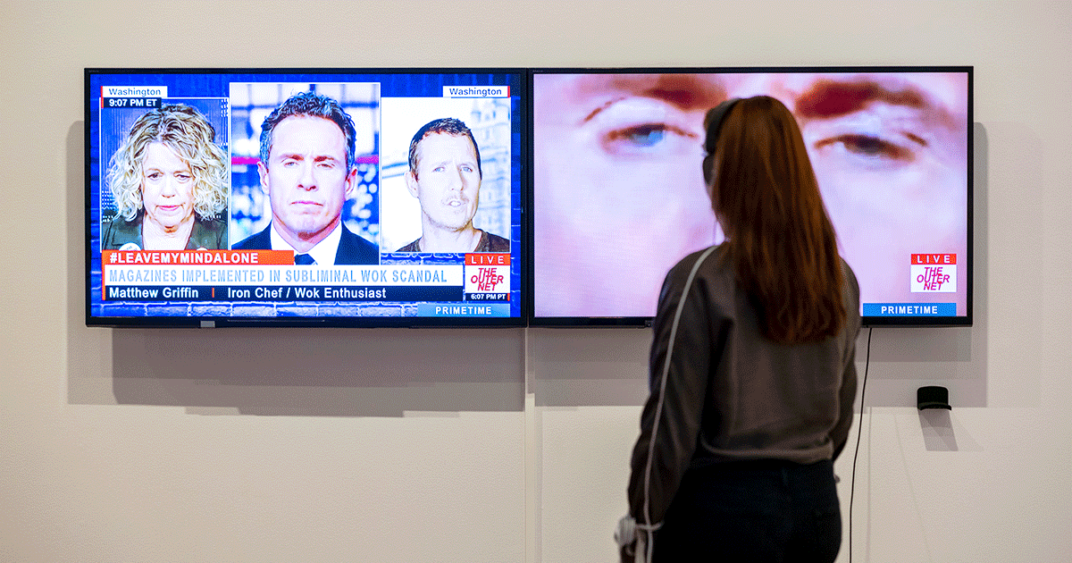 Person wearing headphones standing in front of a video artwork