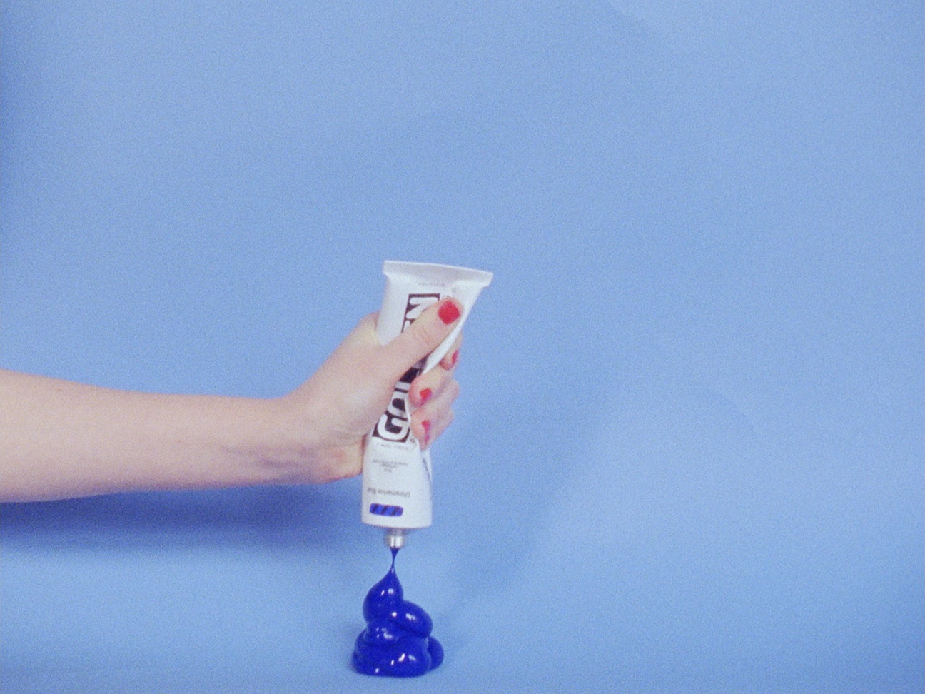 Still from an artwork by Elise Rasmussen showing a hand  squeezing ultramarine paint out of a tube