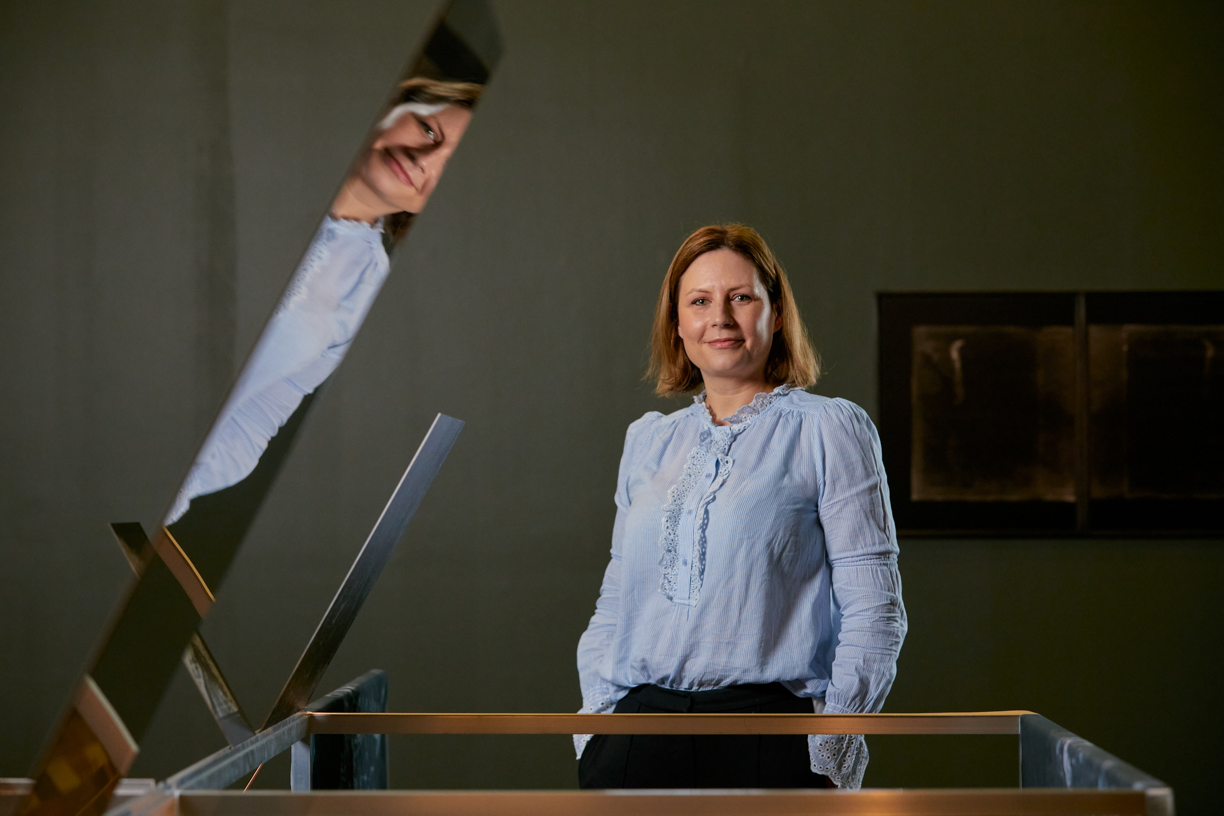 Holly standing next to an artwork and smiling at the camera