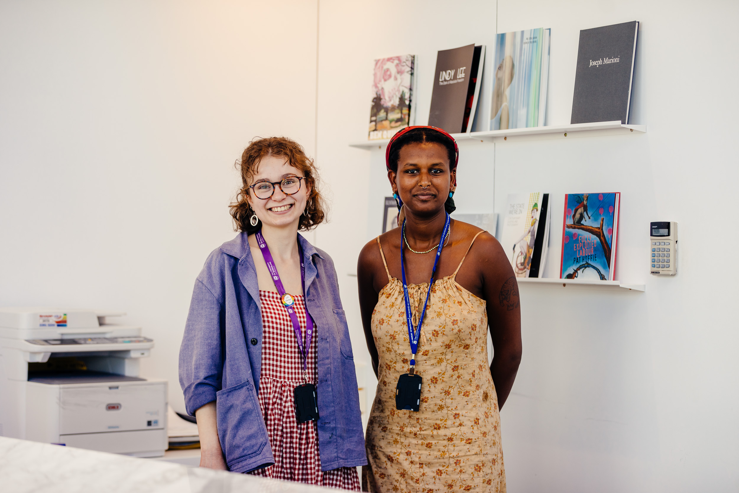 two staff members standing behind the front desk smiling at the camera