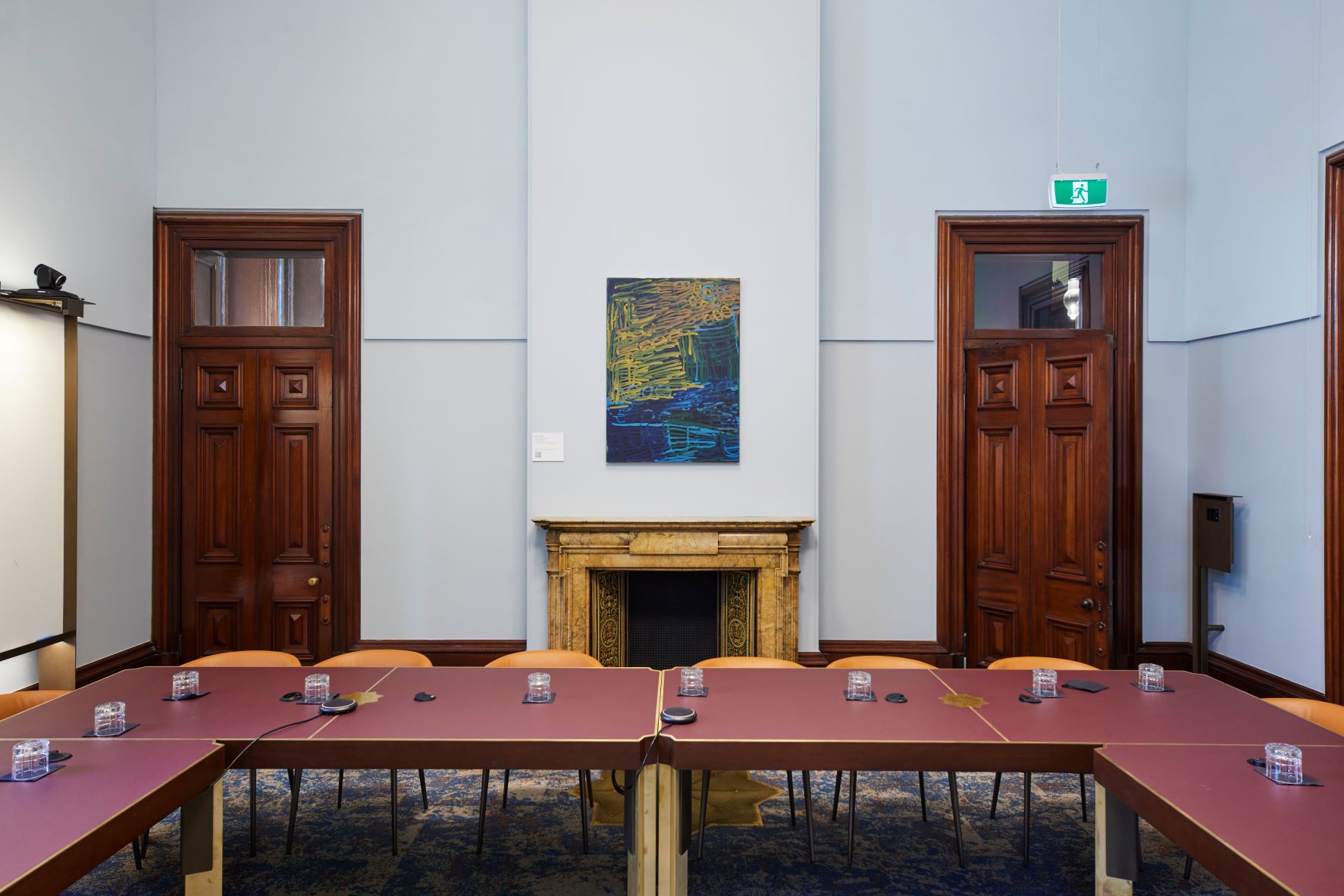 a room with two large wooden doors and a colourful artwork hanging between them