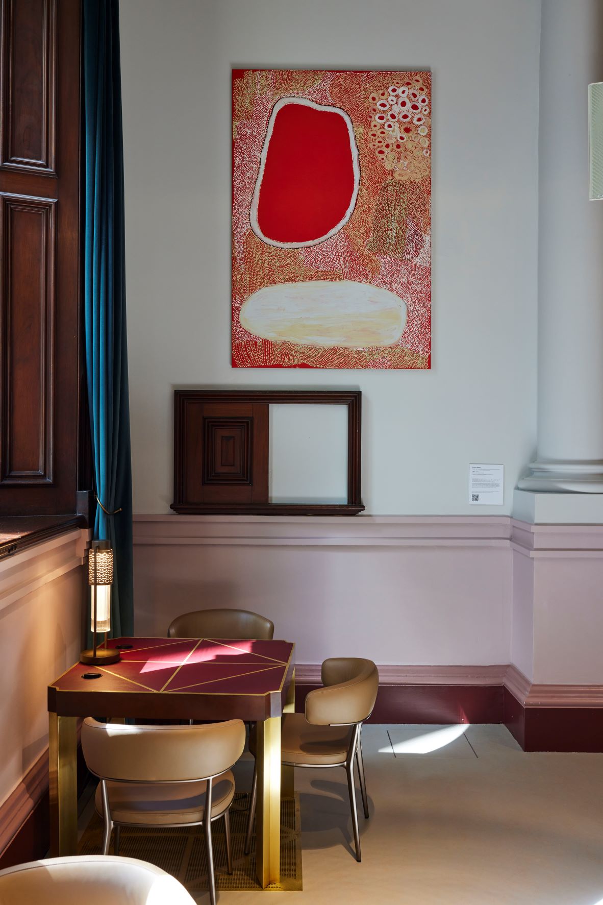 A red and white artwork on display above a desk