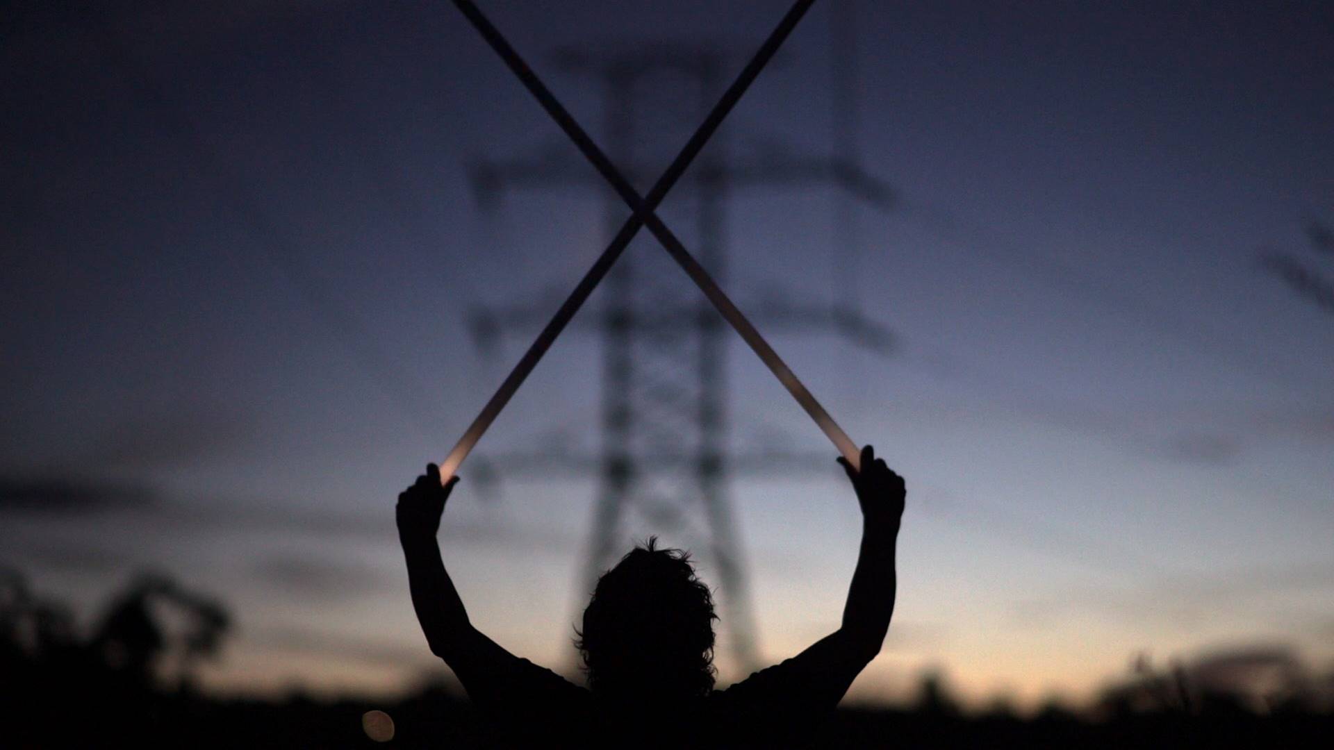 Still from an artwork showing a person holding fluoroescent light tubes