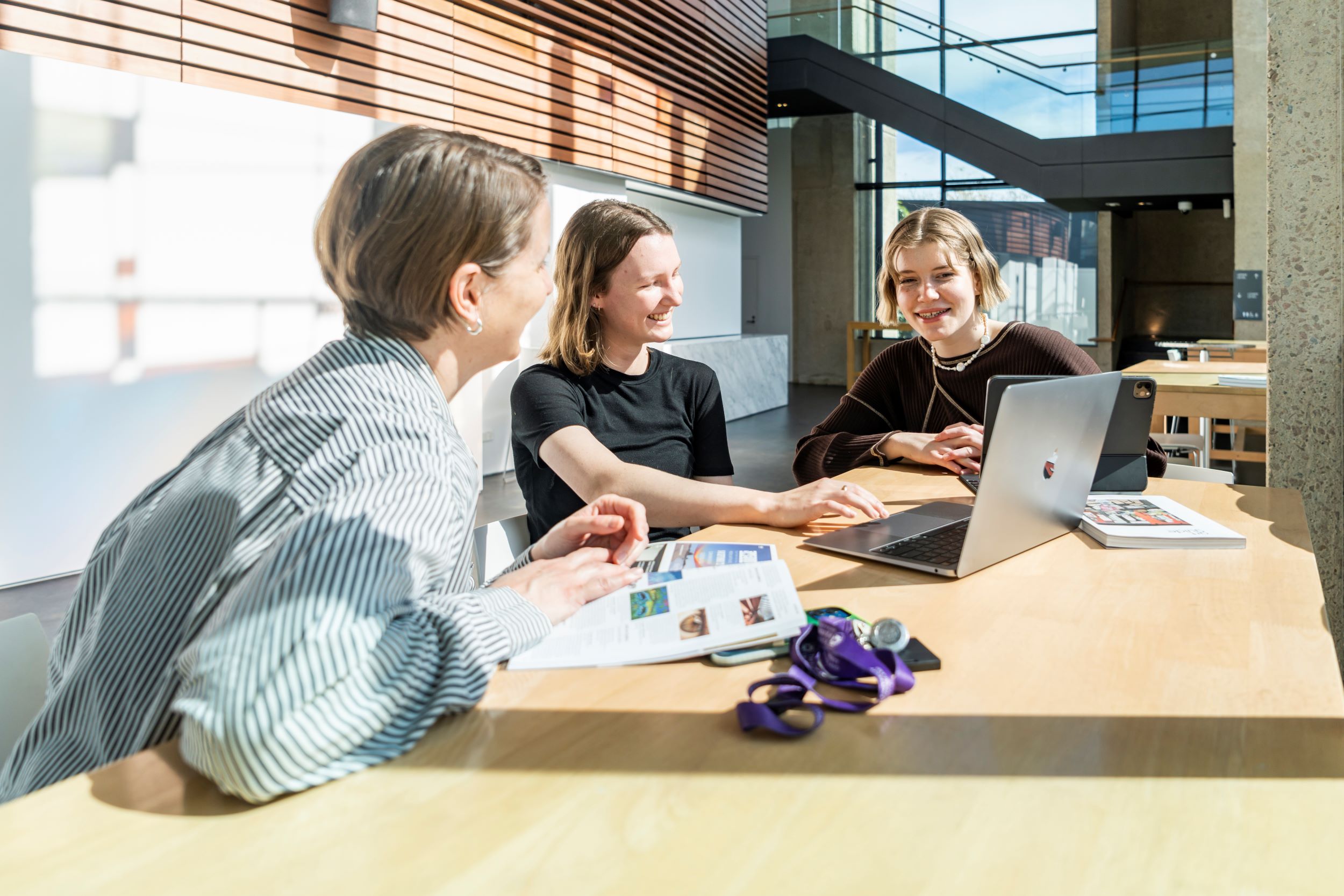 Two interns and their supervisor sitting at a table looking at a laptop screen