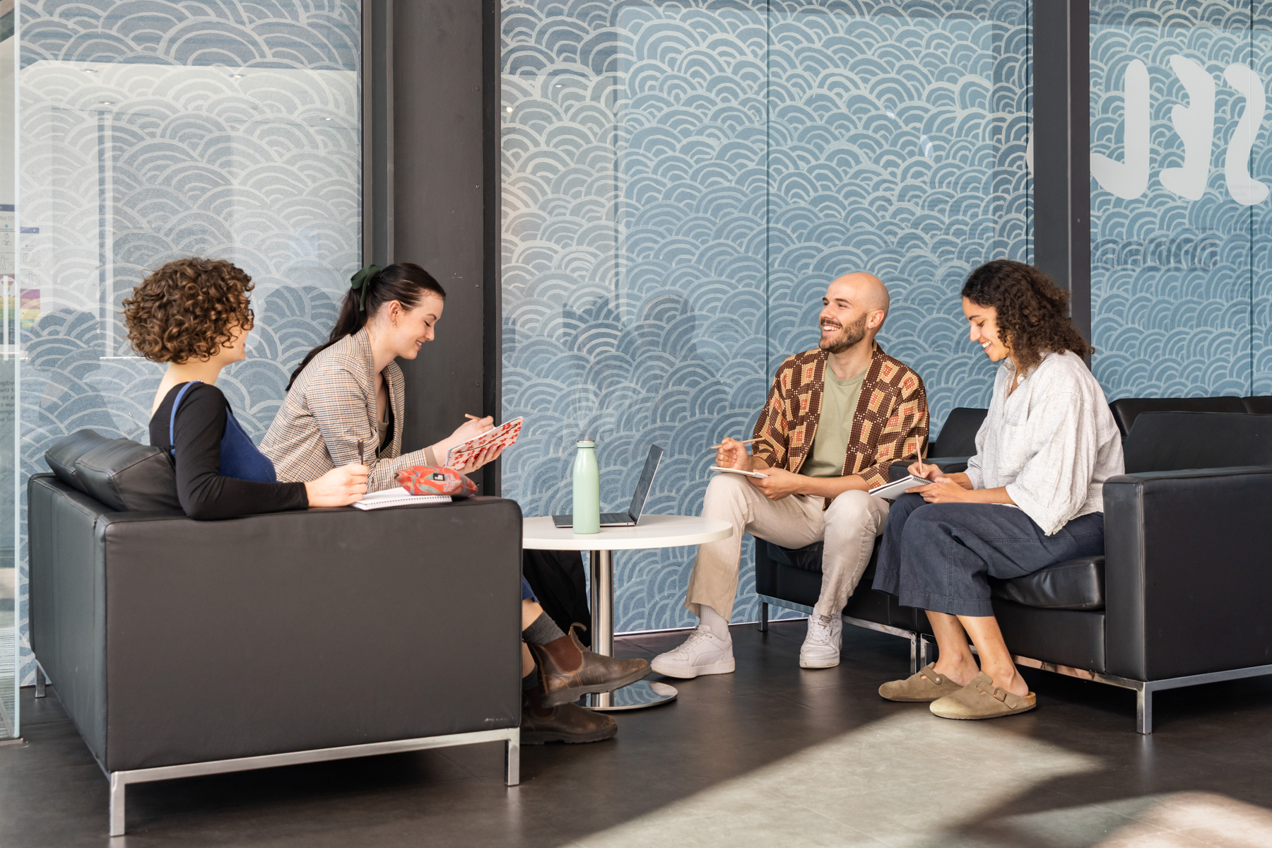 Four mediators sitting together, talking and writing in notebooks