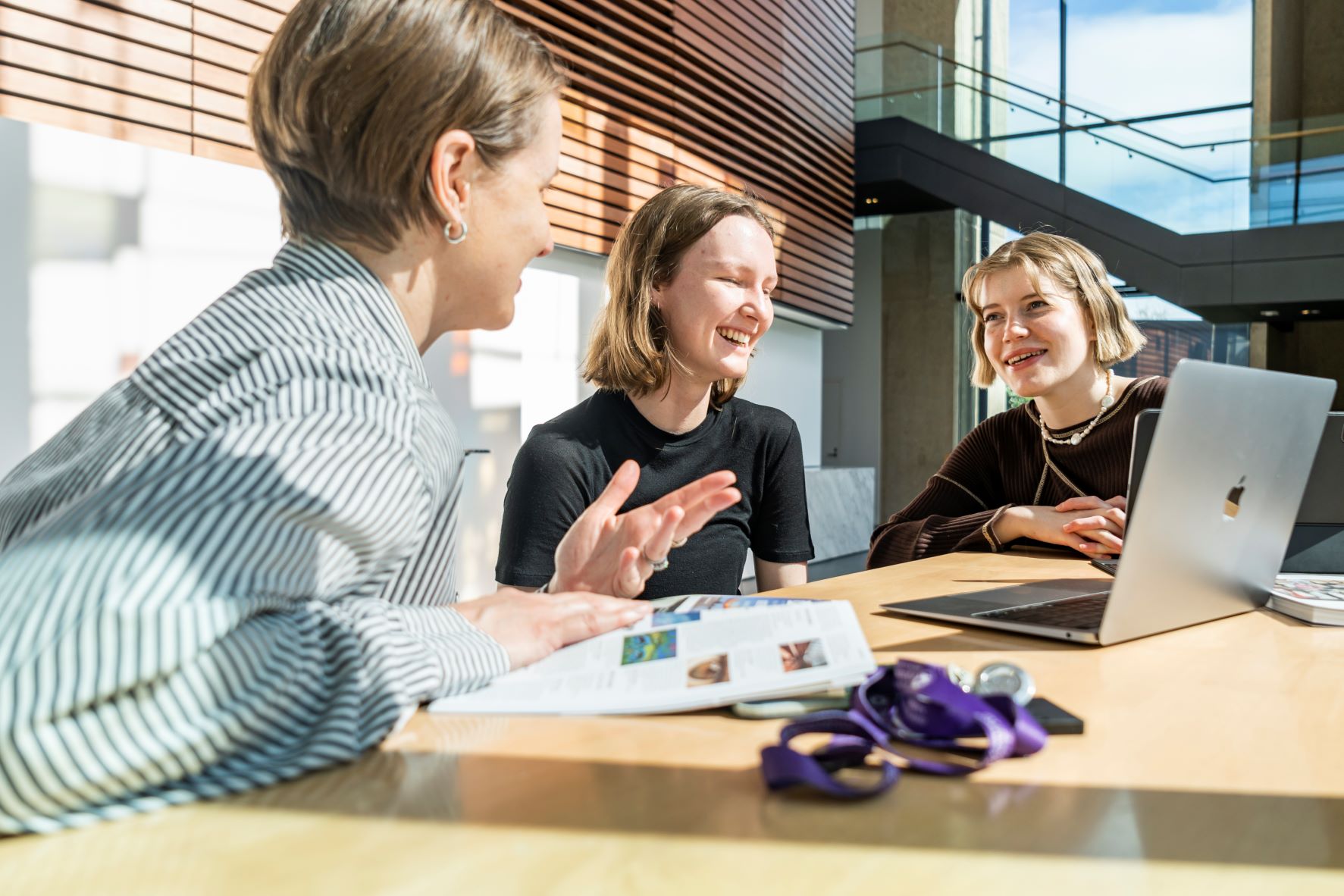 Two students talk with a member of staff