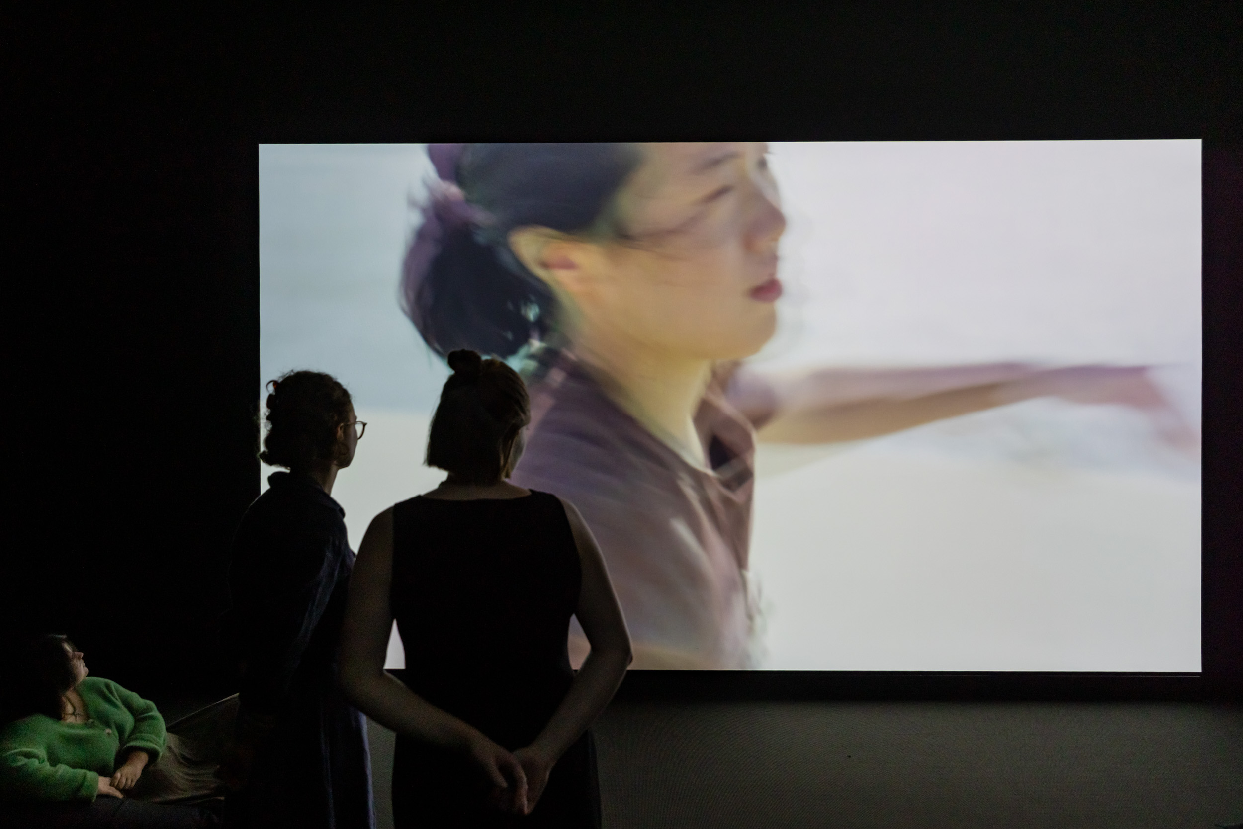 Two people viewing a video artwork