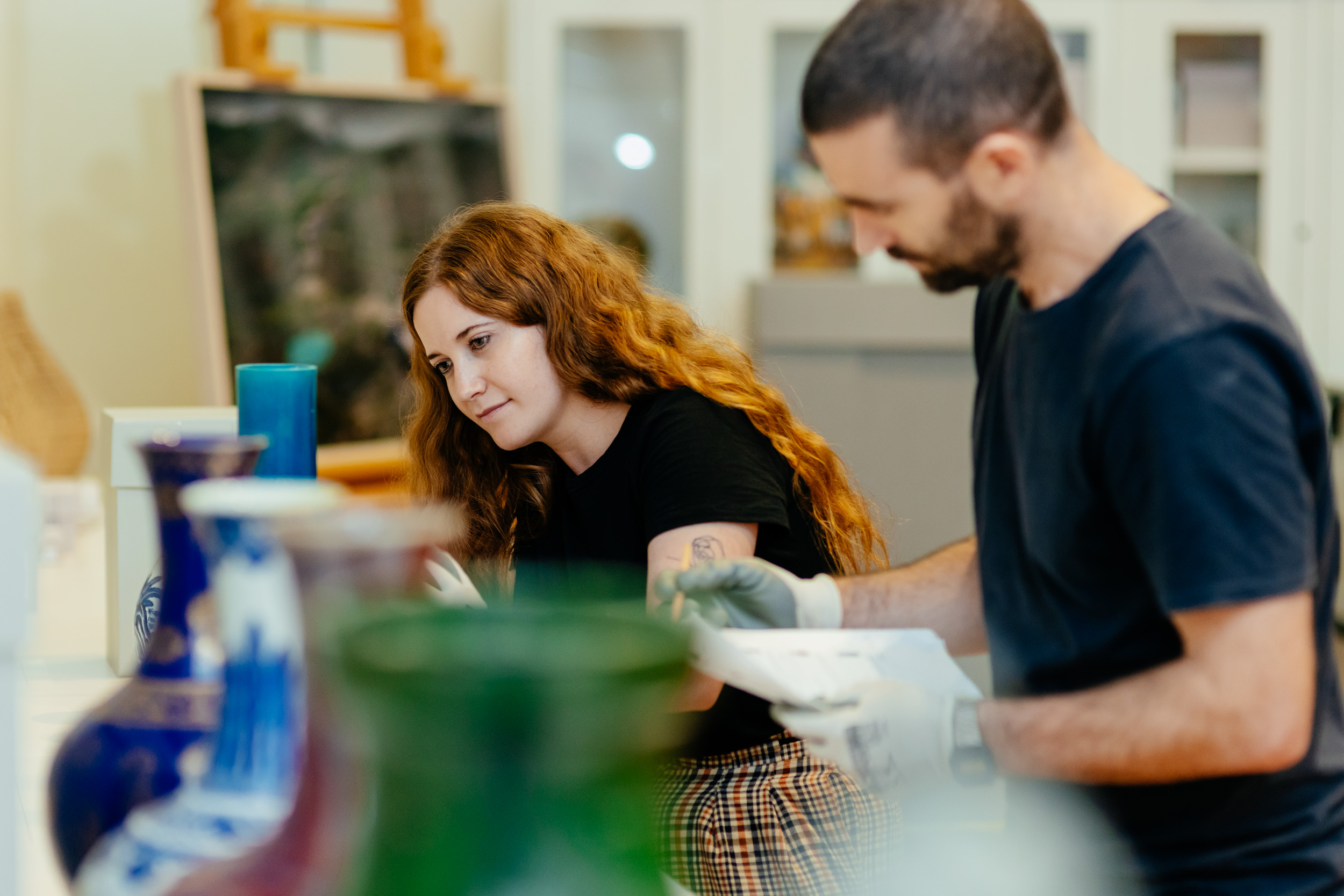 Two staff members looking at a vase