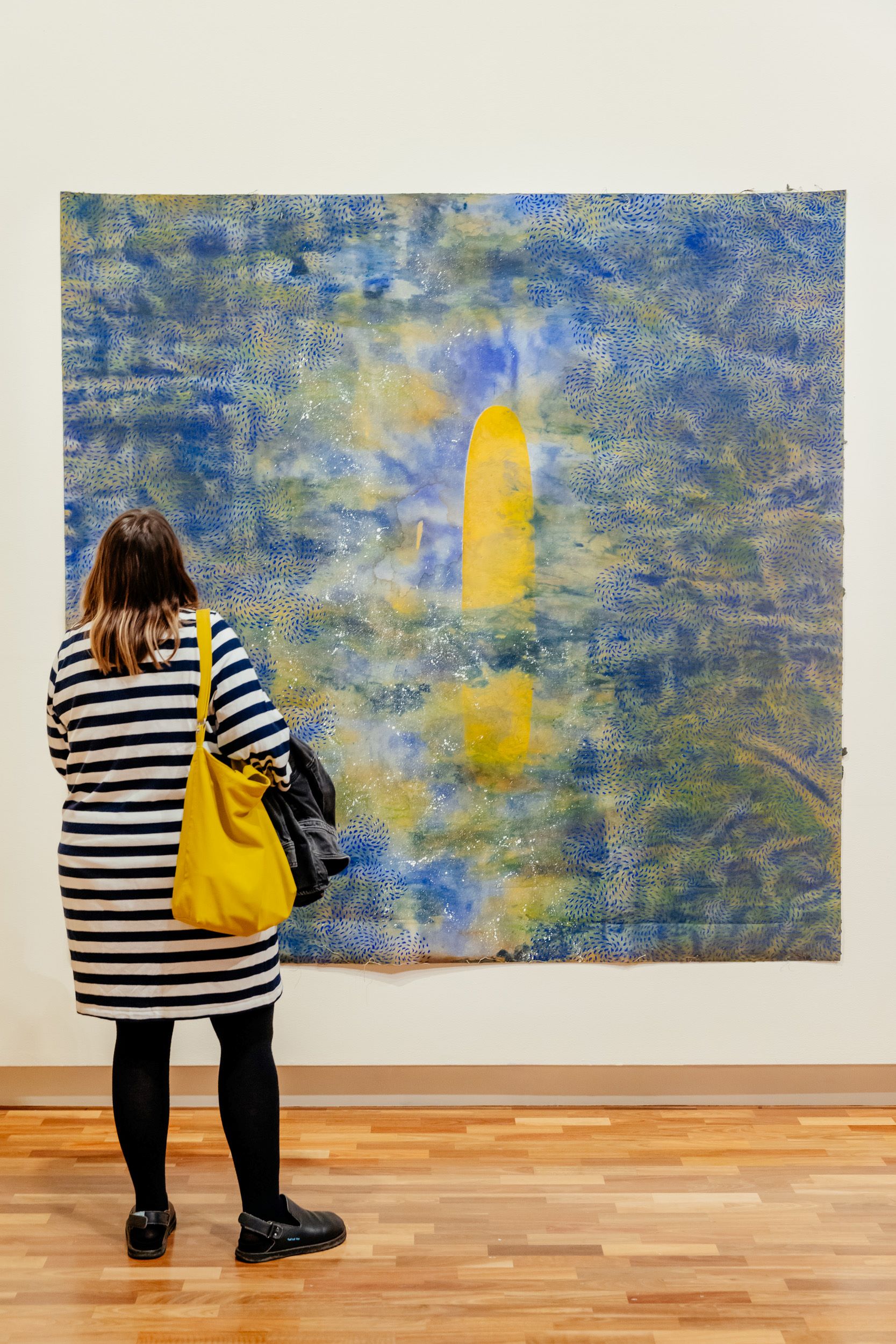 A person views a painting by Judy Watson