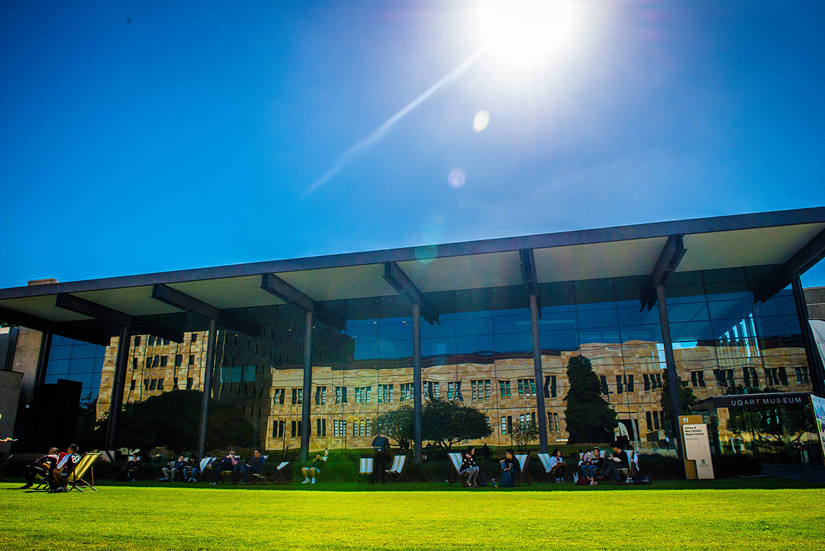 The outside of the art museum building with people sitting on the grass in front of it