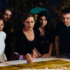 A group of people looking at an artwork on a table