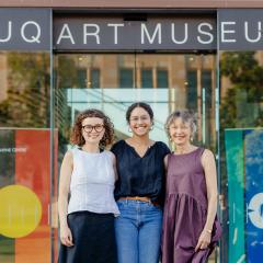 Three smiling people standing in front of UQ Art Museum