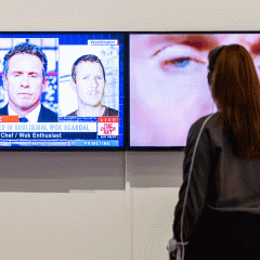 Person standing in front of a video artwork wearing headphones