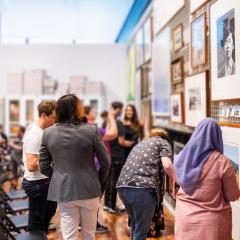 A group of people looking at a gallery hang displaying queer Australian art