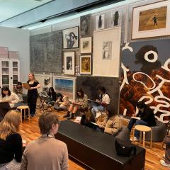 A group of students engage in a life-drawing session while looking at artworks