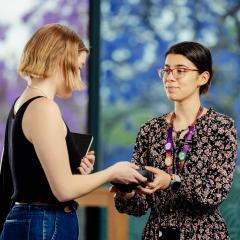 A staff member hands headphones to another staff member