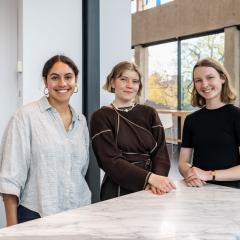 Three students standing in the Art Museum foyer and smiling at the camera